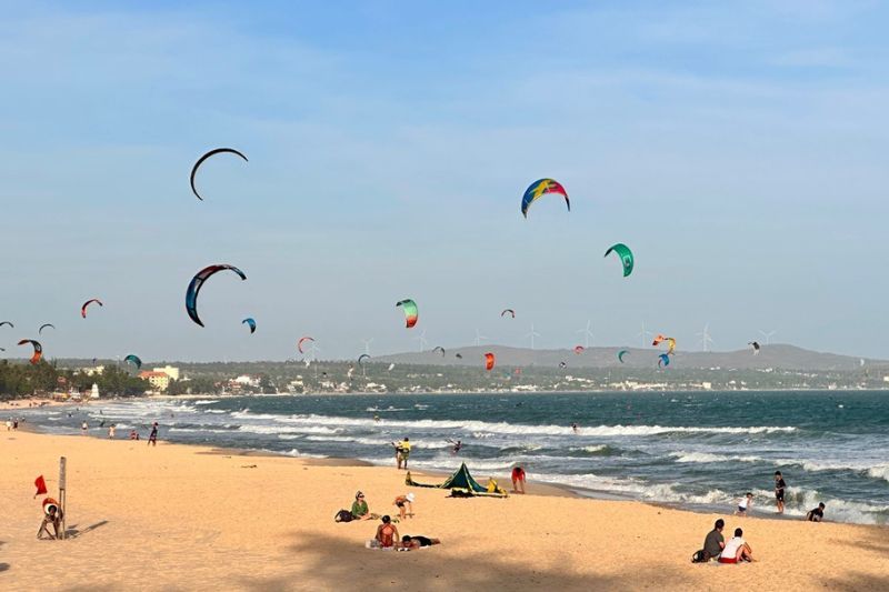 i turisti fanno il bagno e praticano il kitesurf sulla spiaggia di ham tien.