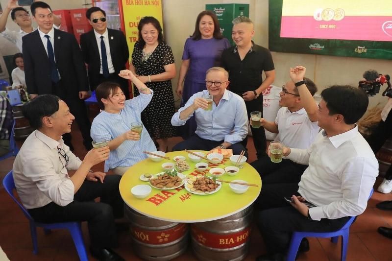 Il primo ministro australiano Anthony Albanese, al centro, beve birra vietnamita
